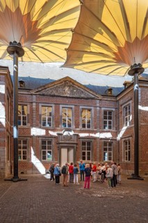 Visitors during guided tour on covered court of honour at Commandery of Alden Biesen, 16th-century