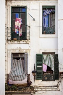 Dilapidated building with colourful cloths on the windows, gives a nostalgic urban charm, window in