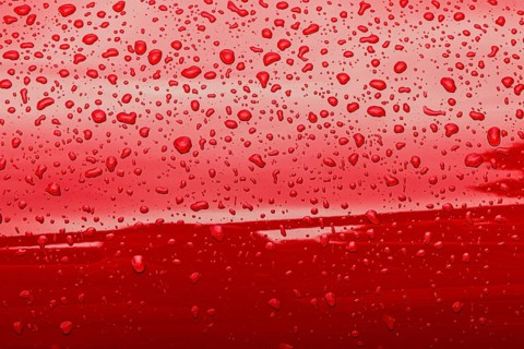 Abstract red background of wet metallic surface with raindrops