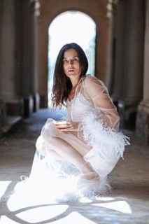 A bride in a delicate white dress poses elegantly in an ancient Italian villa in Treia, Macerata.