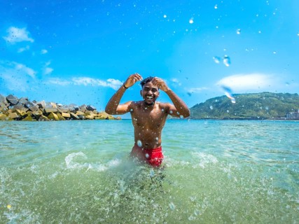 Tourist enjoying a refreshing ocean swim, playfully splashing in the waves under a bright sun on a