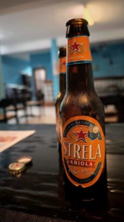 Close-up of a Strela Kriola beer bottle on a table in a restaurant, Ponta do Sol, hiking, Santo