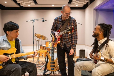 Musicians collaborate in a soundproof recording studio, surrounded by instruments and equipment.