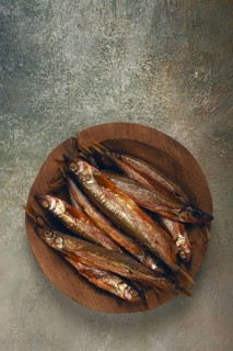 Cold smoked capelin, on a wooden bowl, top view, no people