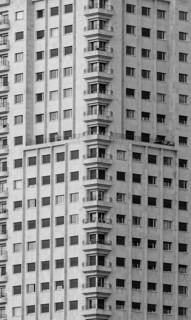 Black and white close-up of a modern high-rise residential building with multiple balconies in
