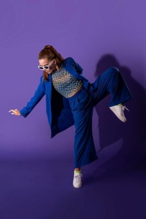 Young woman dancer striking a dynamic pose in a stylish blue outfit with white sneakers, set