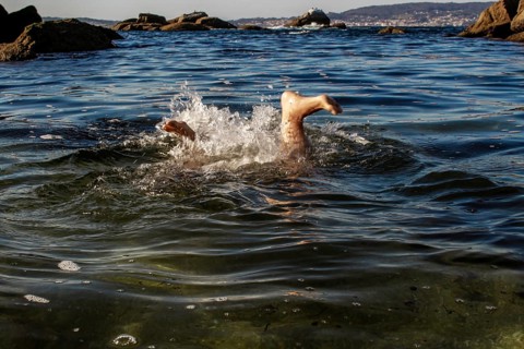 A person is submerged with only their legs visible above the ocean surface. The image captures a