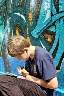 Ten-year-old boy playing with his Nintendo in front of a graffiti wall, football pitch, Germany