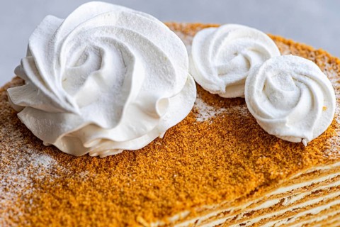 Close up of an homemade honey cake, perfectly complemented by a silky sour cream sauce and