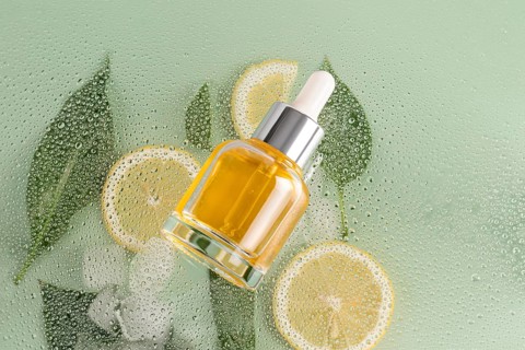 A vibrant skincare serum cosmetic lies on a dewy surface, accompanied by fresh lemon slices and
