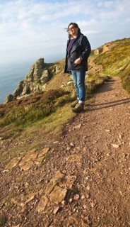 Woman wearing kagoule walking along the South West coast path at St Agnes head, Cornwall, England,