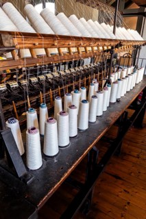 Bramsche, Lower Saxony, Germany, rows of yarn bobbins on an old machine in a textile factory,