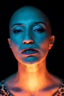 A captivating portrait of a bald woman, illuminated with dynamic lighting in vibrant blues and