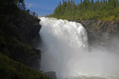 Majestic waterfall surrounded by green forest and blue sky, Tännforsen, Jämtland, Sweden