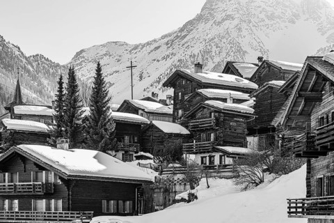Snow-covered old farmhouses, large wooden cross, black and white photo, historic town center,