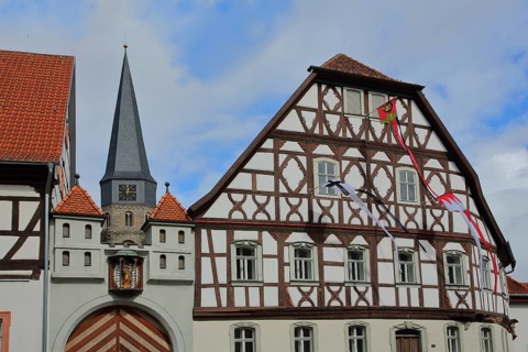Heimatspielhaus with coat of arms and spire of St. Maria Magdalena, half-timbered house with flags,