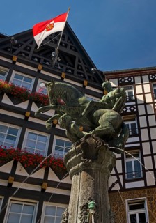 Fountain on the market square with half-timbered houses and flag with town coat of arms, Cochem,