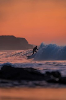 Silhouette of a surfer catching a wave during a vibrant sunset in Fuerteventura, Canary Islands,