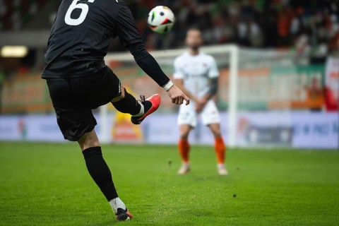 Soccer player kicks the ball during football match. Opponent player in the wall