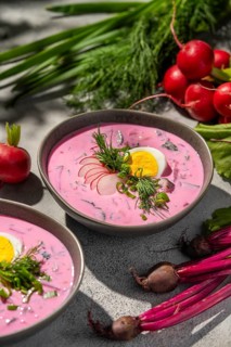 A refreshing bowl of cold beetroot soup served with sliced radishes, hard-boiled eggs, and fresh