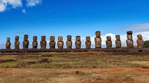 Moai statues under a bright blue sky on a rocky coastal plain, The Moai statues on Easter Island in
