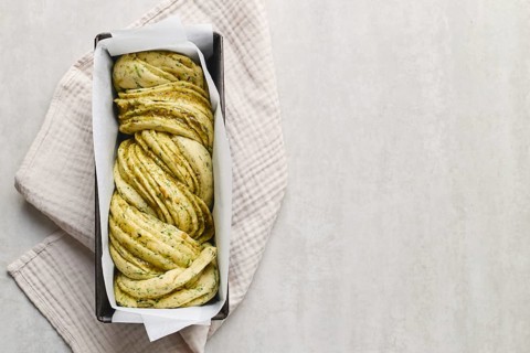 Ready to bake, homemade savoury babka plaited bread loaf flavoured with cheese and pesto, in the
