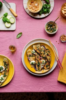 Top view of a vibrant meal presentation featuring roasted courgettes topped with mozzarella, basil,