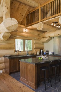 Island with dark grey granite countertop and black stained wooden bar stools in kitchen with