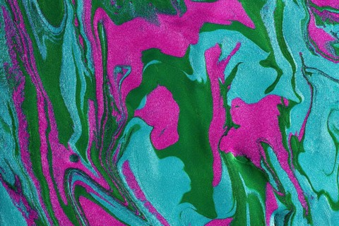 A close-up image of swirling metallic paints mixing pink and green hues, creating a vibrant