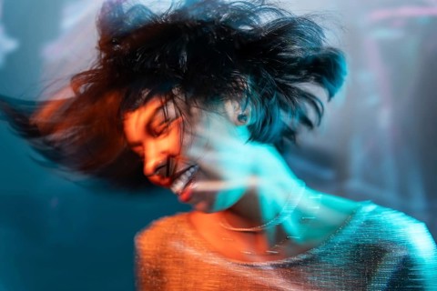 A futuristic Latin woman enjoys a vibrant dance in the metaverse, immersed in a digital realm