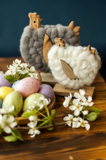 Decorative Easter setup featuring pastel-colored eggs, woolen chicken figures, and delicate white