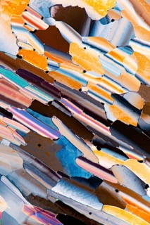A colorful microscopic view of liquid crystals featuring an array of vivid oranges, blues, and