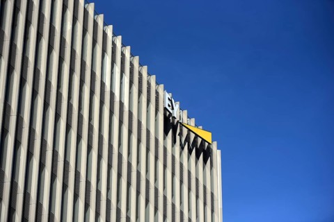 The façade of a modern EY office building with repetitive vertical slats, clear lines and a company