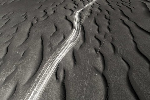 A striking image capturing the unique textures of black sand, highlighted by natural ripple
