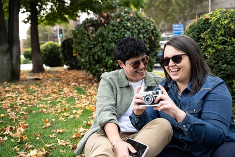 A cheerful curvy couple enjoys a day in the park, sharing moments and taking photos with a vintage