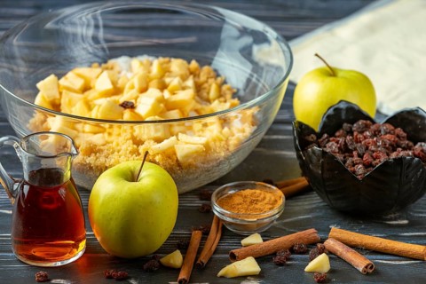 Apple pieces in a bowl with raisins, cinnamon and rum