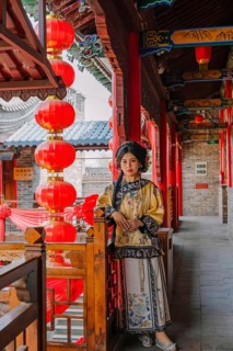 Woman in traditional Qing dynasty attire stands gracefully in a historic corridor in Pingyao,