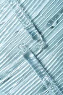 Top view of transparent gel smears with pipettes on clear glass. The texture and shine illustrate a