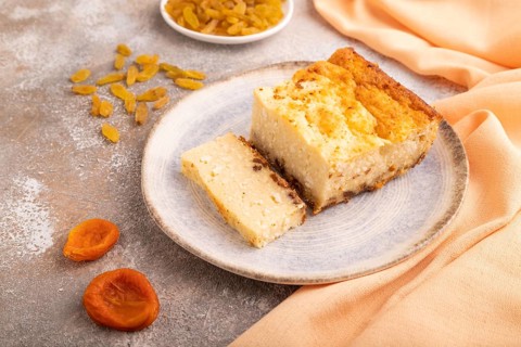 ?ottage cheese ?asserole, Curd cake, with dried apricots and raisins on brown concrete background
