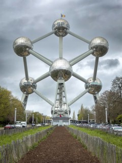 The Atomium with a wooden-bordered bark mulch path in the foreground under cloudy sky, Brussels,