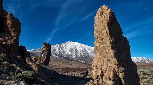 Roques de Garcia, an impressive rock formation in front of a snow-covered mountain under clear blue