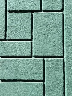 Detailed image of a green brick wall showcasing a geometric pattern. The textured surface and