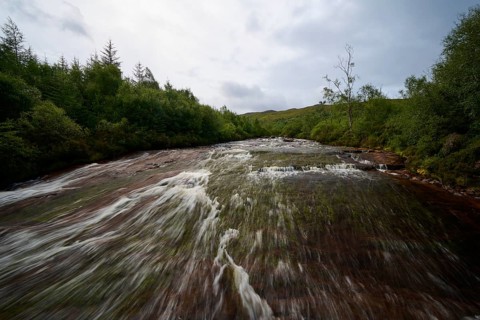 A calm river flows through a forest under cloudy skies, Victoria Falls, Slattadale, Achnasheen,