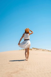 Vertical photo of an elegant woman in summer white dress on a dune in Cabo de Gata, Spain