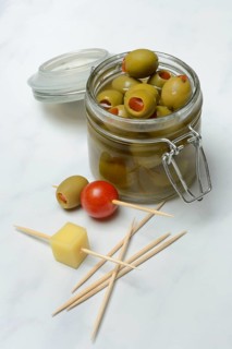 Green olives in glass and on toothpicks with tomato and cheese cubes