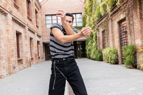 A Cuban man passionately dances outdoors in an urban courtyard, showcasing vibrant movement and