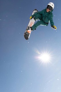 A snowboarder performs a high-flying trick against a crisp blue sky, capturing the thrilling