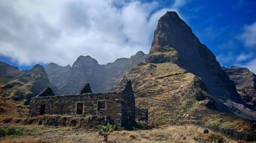 Ruin in front of a majestic mountain peak with clouds and clear sky, hiking, lost place, abandoned
