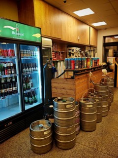 Beverage market with beer kegs, cooling rack and wooden bar in industrial style, draft beer in