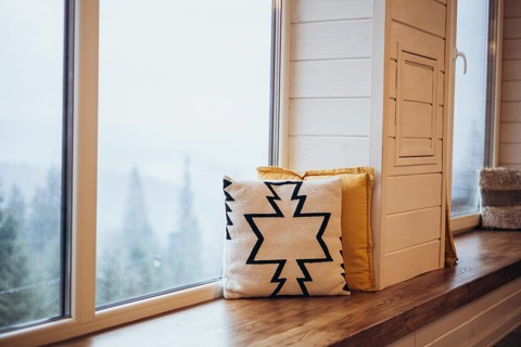 A snowy landscape is visible through a large window, enhanced by a comfortable window seat adorned